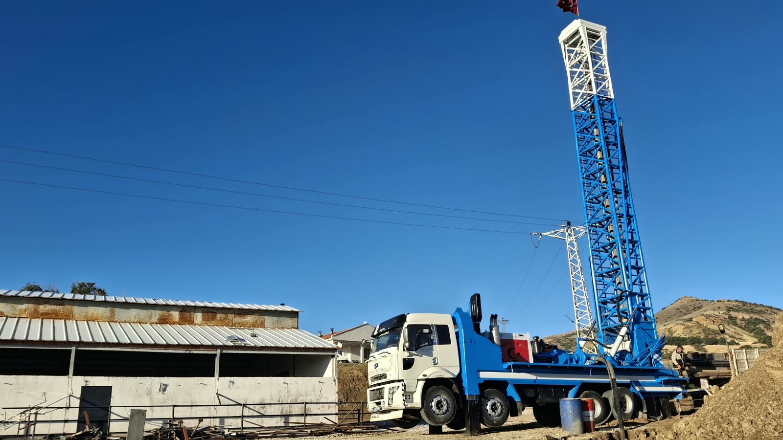 Serin Sondaj'ın mavi-beyaz sondaj kulesi ve beyaz Ford Cargo kamyonu, açık mavi gökyüzü